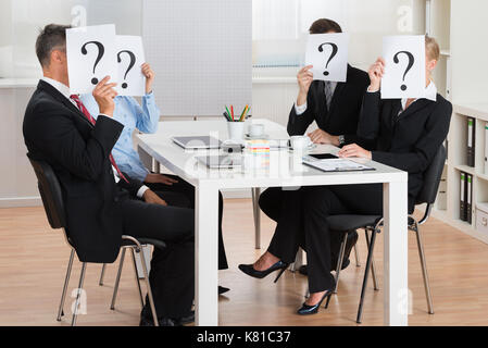 Gruppo di imprenditori volti nascosti dietro il punto interrogativo firmare in sala conferenze Foto Stock