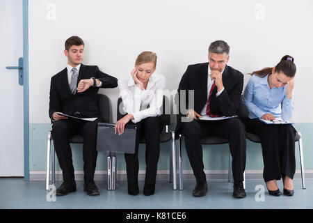 Gli imprenditori seduti su una sedia in attesa per il colloquio di lavoro in ufficio Foto Stock