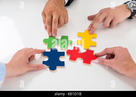 Close-up di gente colorata di assemblaggio i pezzi del puzzle al banco Foto Stock