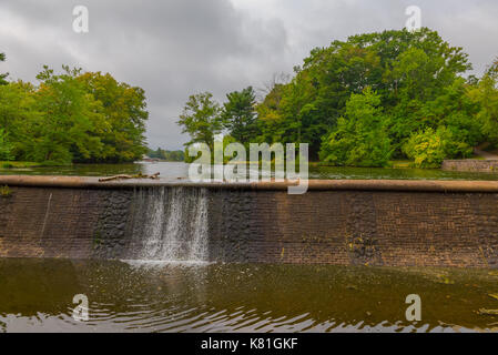 Una piccola cascata alimentata da un lago in un parco. Foto Stock
