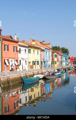 Case colorate su Burano, Venezia, Veneto, Italia in mattina presto luce riflessa nell'acqua ancora del canale sottostante Foto Stock