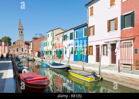 Vista lungo il canal del XVI secolo Chiesa di San Martino , Burano, Venezia, Veneto, Italia con il suo campanile pendente in Early Morning Light Foto Stock