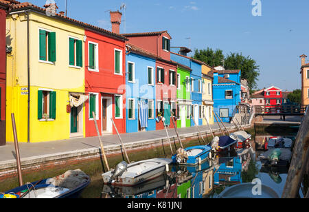Fila di bright case colorate di sunrise, Burano Venezia Italia riflette in un tranquillo canale Foto Stock