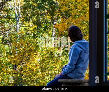 Young Teen seduto all'esterno guardando gli alberi Foto Stock