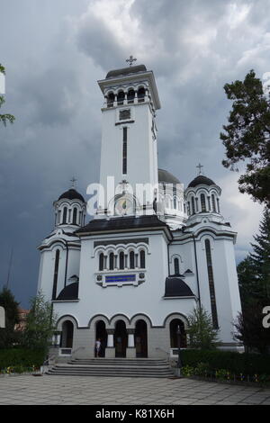 Chiesa della Santissima Trinità con bandiera rumena e cielo nuvoloso. Sighisoara, Transilvania, Romania Foto Stock