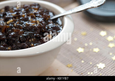 Macro immagine di mincemeat natalizio tradizionale fatto in casa con frutta mista e brandy in una ciotola bianca, messa a fuoco sul soggetto, sfondo de messo a fuoco Foto Stock