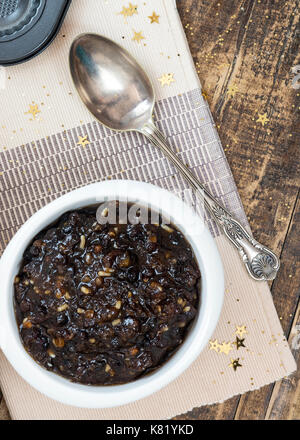 Immagine verticale di mincemeat natalizio tradizionale fatto in casa con frutta mista e brandy in una ciotola bianca, mettere a fuoco sul soggetto , sfondo de focu Foto Stock