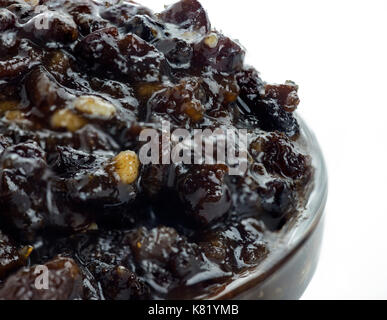 Extreme macro shot di casereccia tradizionale di Natale fatto in casa con frutta mista e brandy in una ciotola di vetro su uno sfondo bianco isolato Foto Stock