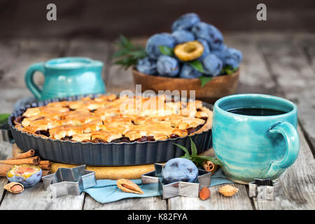 In casa tradizionale torta di prugne con cinamon e mandorle con caffè sul vecchio sfondo di legno Foto Stock