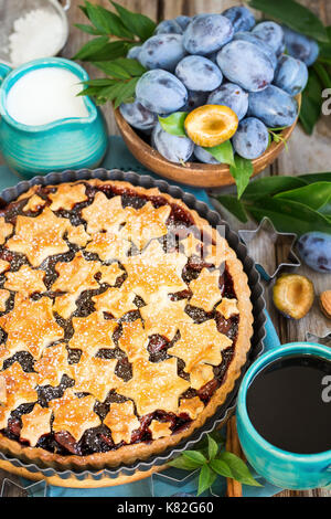 In casa tradizionale torta di prugne con cinamon e mandorle con caffè sul vecchio sfondo di legno Foto Stock