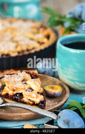 In casa tradizionale torta di prugne con cinamon e mandorle con caffè sul vecchio sfondo di legno Foto Stock