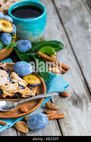 In casa tradizionale torta di prugne con cinamon e mandorle con caffè sul vecchio sfondo di legno Foto Stock