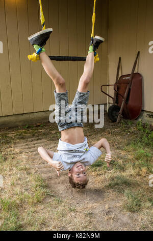 Quattordici anni di vecchio ragazzo dimostrando la sua maestria del trapezio nel suo cortile Foto Stock