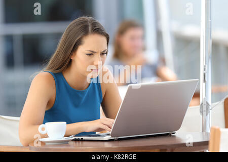 Preoccupati singola donna che utilizza un computer portatile seduto in un bar terrazza Foto Stock