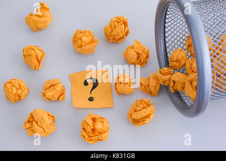 Giallo carta sgualcita di sfere e punto interrogativo rolling out di un cestino. close up. Foto Stock