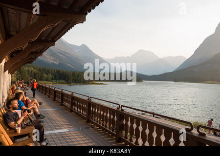 Gli ospiti del lodge swiftcurrent seduti sul balcone che si affaccia sul lago e godersi il tramonto sulla calda serata estiva Foto Stock