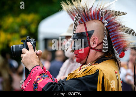 Guerriero indigeno del Canada, nativo maschile, Wahta Mohawk/Irochesi che utilizza una fotocamera reflex digitale Canon per fotografare un incontro Pow Wow a Londra, Ontario, Canada. Foto Stock