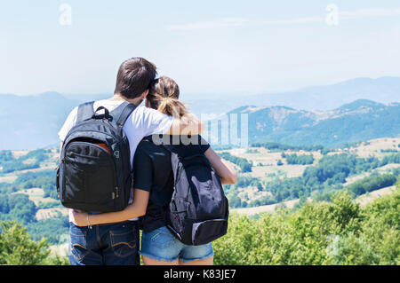 Paio di escursionisti con zaini permanente al punto di vista e godendo di una vista della valle. coppia di attività condivisa Foto Stock