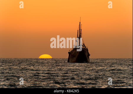 Ocean sunset nave silhouette è una vecchia nave di legno seduta in mare guardando il tramonto sull'oceano orizzonte. Foto Stock