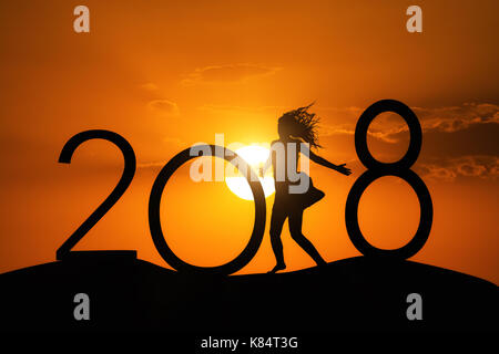 Silhouette persona saltando 2018 sulla collina al tramonto Foto Stock