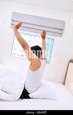 Giovane uomo asiatico il risveglio e stirando le braccia al mattino Foto Stock
