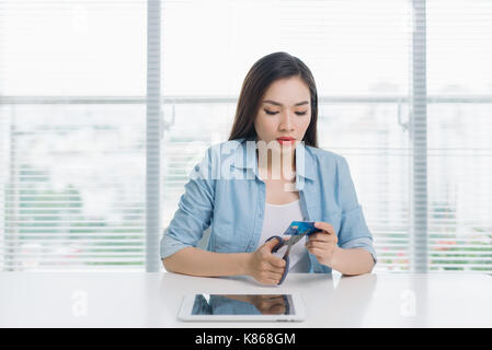 Femmina asiatica shopping il taglio la sua carta di credito con le forbici Foto Stock