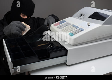 Ladro in passamontagna maschera rubare i soldi dal registratore di cassa Foto Stock