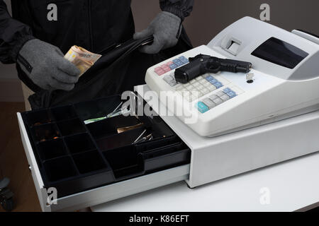 Close-up del rapinatore mani tenendo la carta moneta dal registratore di cassa Foto Stock