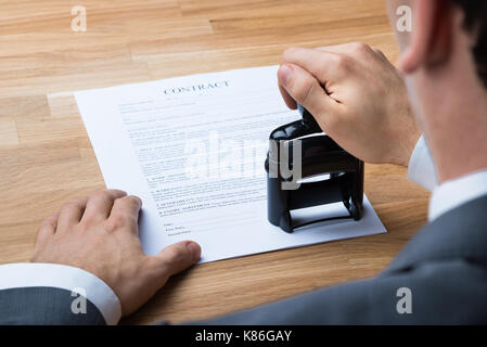 Immagine ritagliata di imprenditore timbratura documento contrattuale a scrivania da ufficio Foto Stock