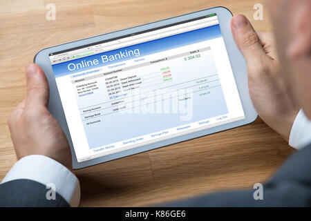 Immagine ritagliata di imprenditore facendo il banking online su tavoletta digitale a scrivania da ufficio Foto Stock