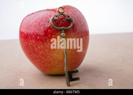 Mano che tiene una chiave accanto a una mela rossa Foto Stock