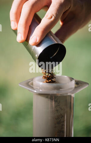 Delizioso macinato di fresco la mattina i chicchi di caffè che è gettato in manuale caffè macinacaffè, vista ravvicinata. processo di bollitore per caffè Foto Stock