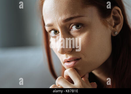 Ritratto di un triste cupo donna tiene il mento Foto Stock