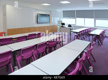 Una moderna classe in una nuova scuola secondaria londinese. Mostra il layout tradizionale con scrivanie di fronte a un grande computer monitor.vuoto, nessun alunni. Foto Stock