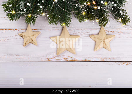 Le decorazioni di Natale in bianco sullo sfondo di legno. vintage stelle e luci sopra la testa vista Foto Stock