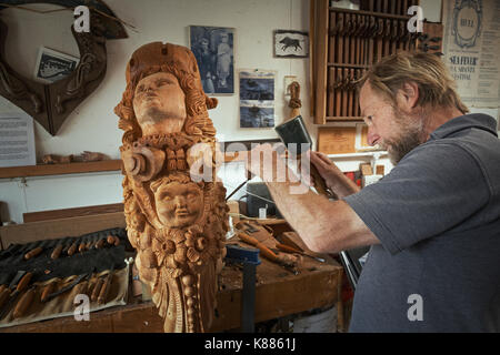 Un artigiano, carver lavorando su un intaglio con un martello e uno scalpello piccola marcatura del legno e aggiunta di texture e di forma. una femmina di legno della nave figureh Foto Stock