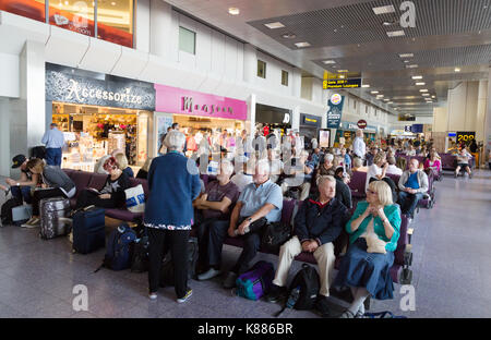 I passeggeri seduti nella sala partenze, terminale 2, aeroporto di Manchester, in Inghilterra, Regno Unito Foto Stock