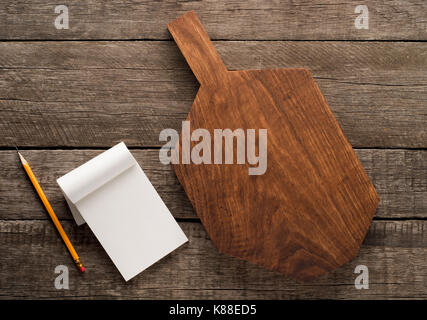 Tagliere e cookbook su sfondo di legno Foto Stock