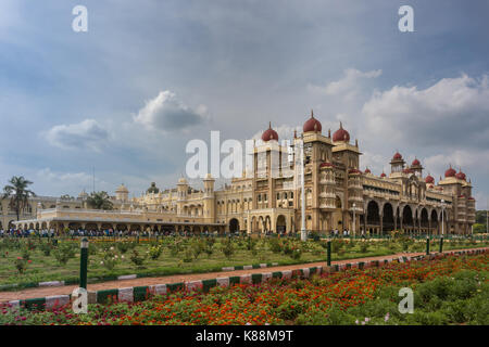 Mysore, India - 27 ottobre 2013: ampio riprese al di fuori del giardino del sud ed est facciate di Mysore Palace sotto cloudscape. edificio giallo con torri e Foto Stock