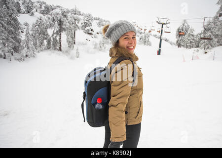 Donna escursioni invernali. bellissima giovane donna caucasica godendo di neve vestito in un allegro Cappello invernale e con una tasca sulla schiena con copyspace. Foto Stock