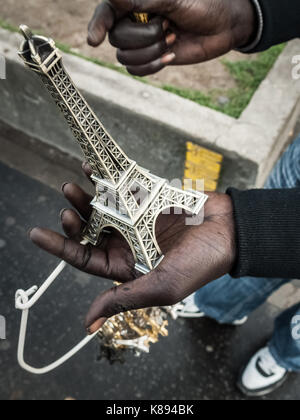 Un illegale street venditore offre miniature della Torre Eiffel in vendita a Parigi, Francia. Foto Stock