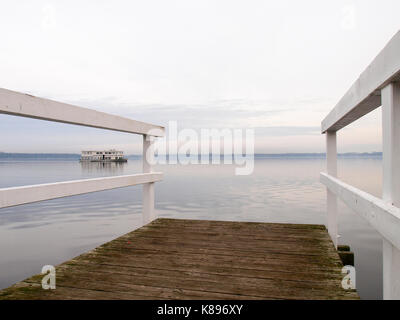 Bad Zwischenahn, Germania - 23 novembre 2016: in legno bianco dock in barca sul lago al tramonto Foto Stock