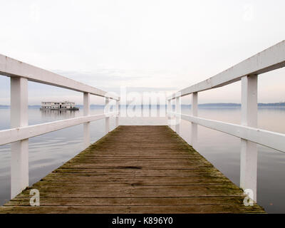 Bad Zwischenahn, Germania - 23 novembre 2016: in legno bianco dock in barca sul lago al tramonto Foto Stock