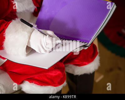 Santa messa a una lista di regali Foto Stock