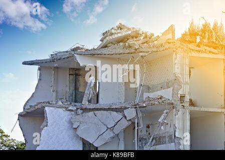 La rovina di un parzialmente demolito palazzo residenziale (piano superiore) davanti a un cielo blu con nuvole bianche Foto Stock