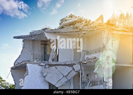 La rovina di un parzialmente demolito palazzo residenziale (piano superiore) davanti a un cielo blu con nuvole bianche, soleggiato con lens flare Foto Stock