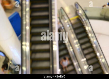 Abstract sfocato delle scale mobili con persone di andare verso il basso in un centro commerciale per lo shopping Foto Stock