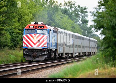 Un westbound Metra treno il trasporto pendolari da Chicago suburbana attraverso Bartlett, Illinois, Stati Uniti d'America. Foto Stock