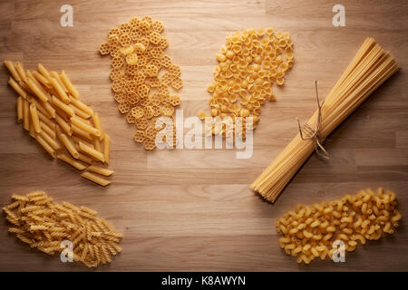 Chiudere fino a diversi tipi di pasta secca luce sul tavolo di legno, vista dall'alto Foto Stock
