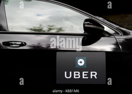 Una Volkswagen nera con il logo Uber è usato come un taxi e mostra anche un driver in una verdeggiante strada suburbana NEL REGNO UNITO (solo uso editoriale). Foto Stock